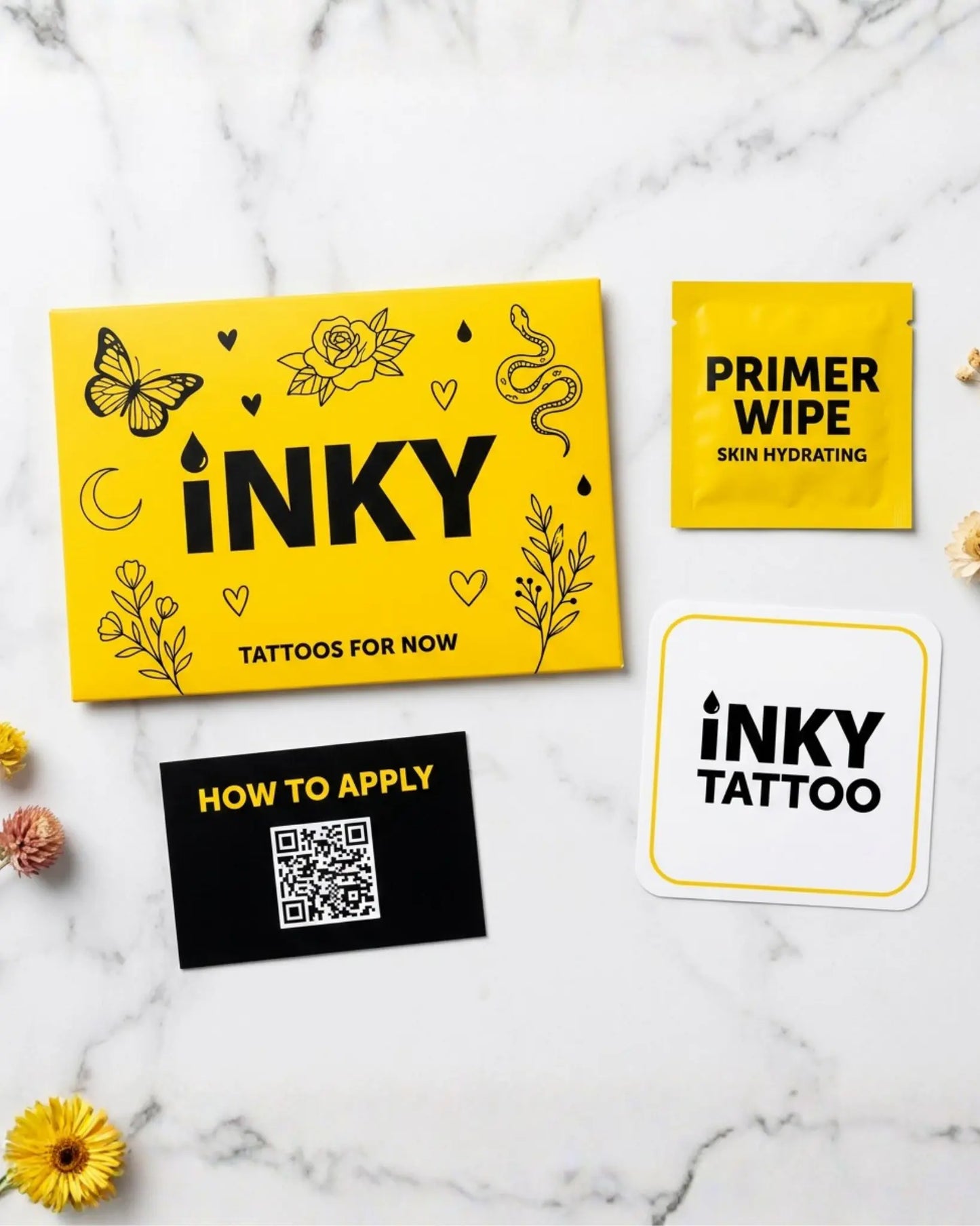 INKY Tattoos For Now complete packaging kit on marble surface – yellow branded envelope with floral and butterfly illustrations, skin hydrating primer wipe sachet, how to apply instruction card with QR code, and INKY Tattoo branded sticker