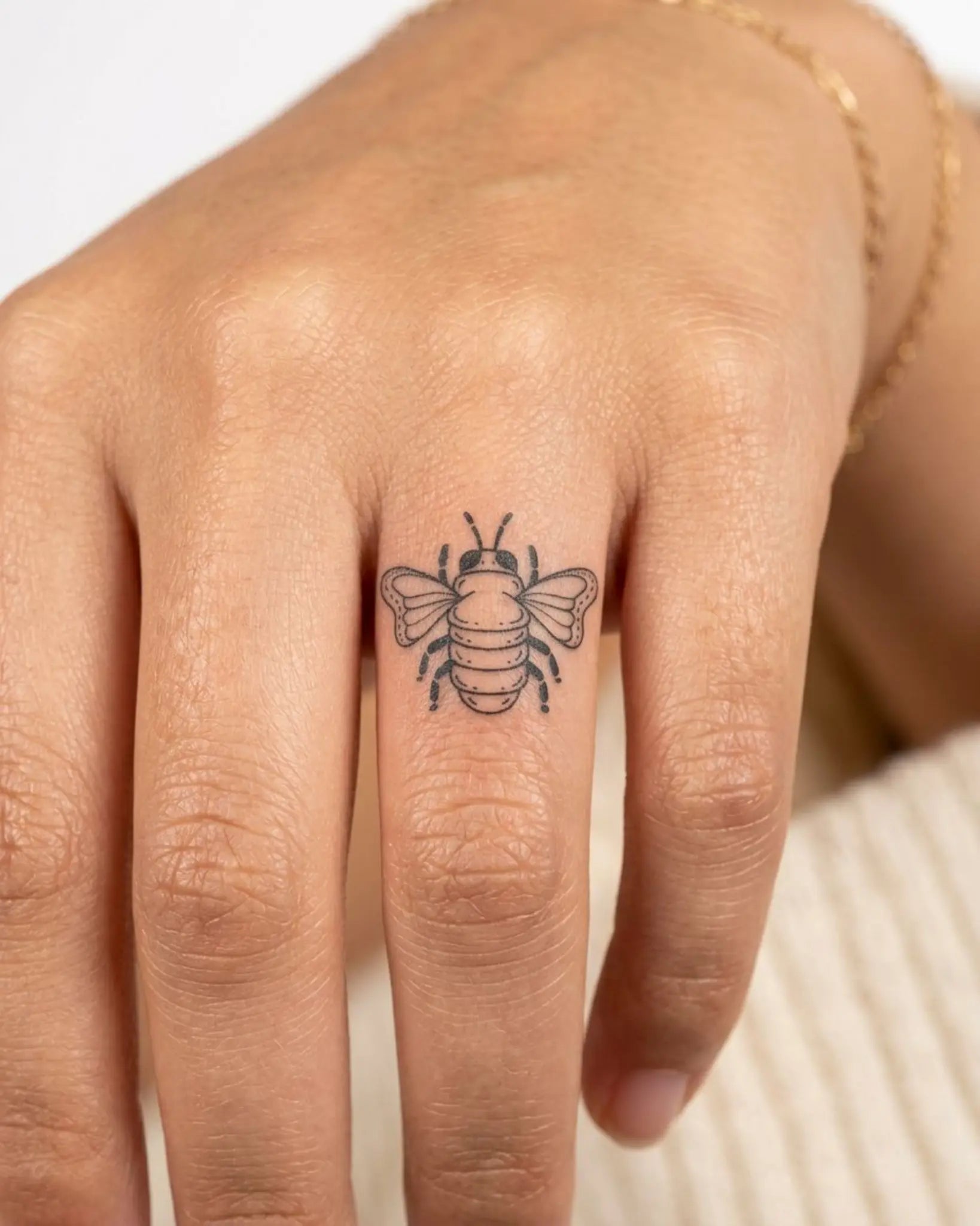 INKY Little Bee semi-permanent tattoo applied on a woman – 0.5 x 0.5 in (1x1 cm) design, realistic ink look, lasts 10 days