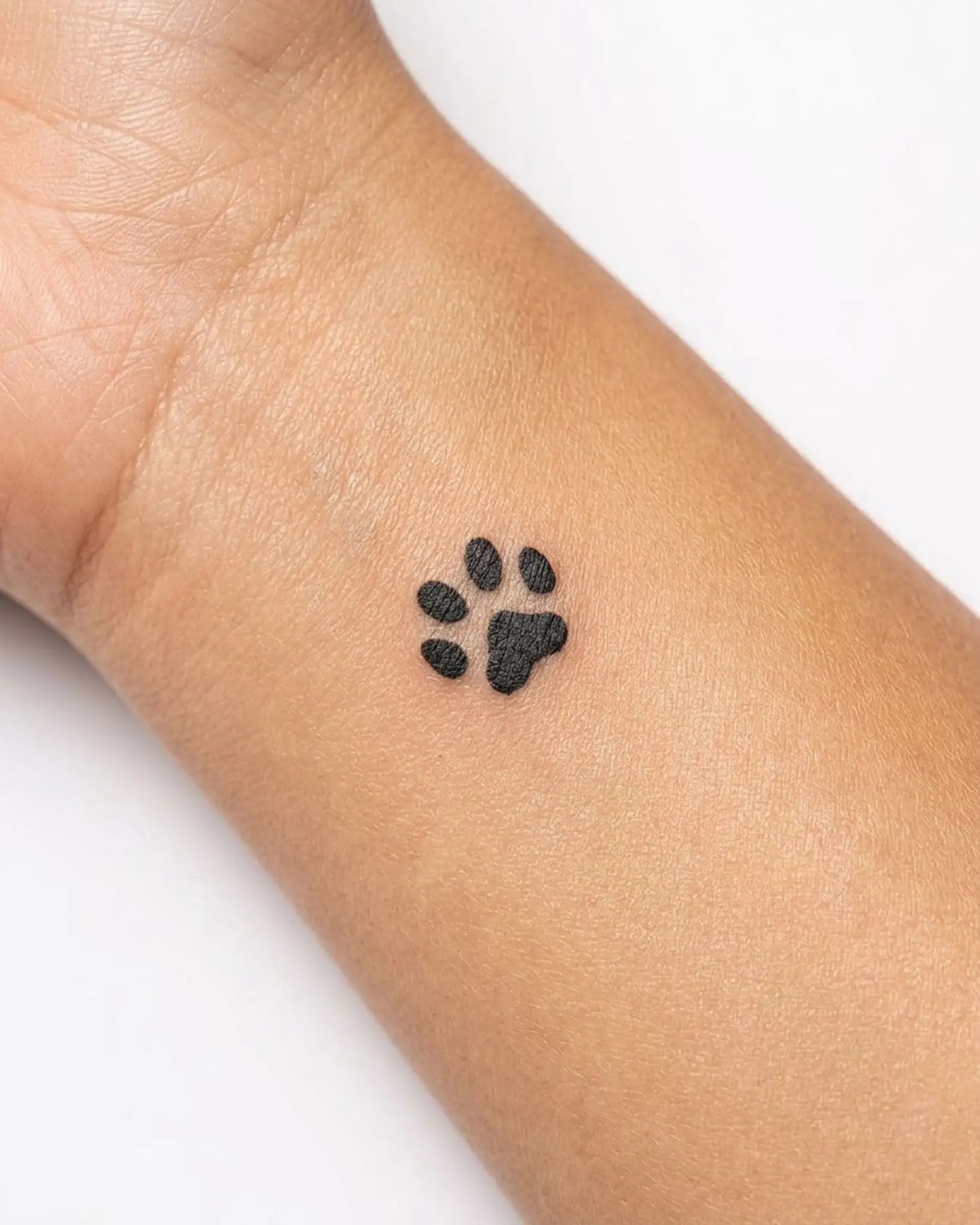 INKY Paw Print semi-permanent tattoo applied on a woman – 0.5 x 0.5 in (1x1 cm) design, realistic ink look, lasts 10 days