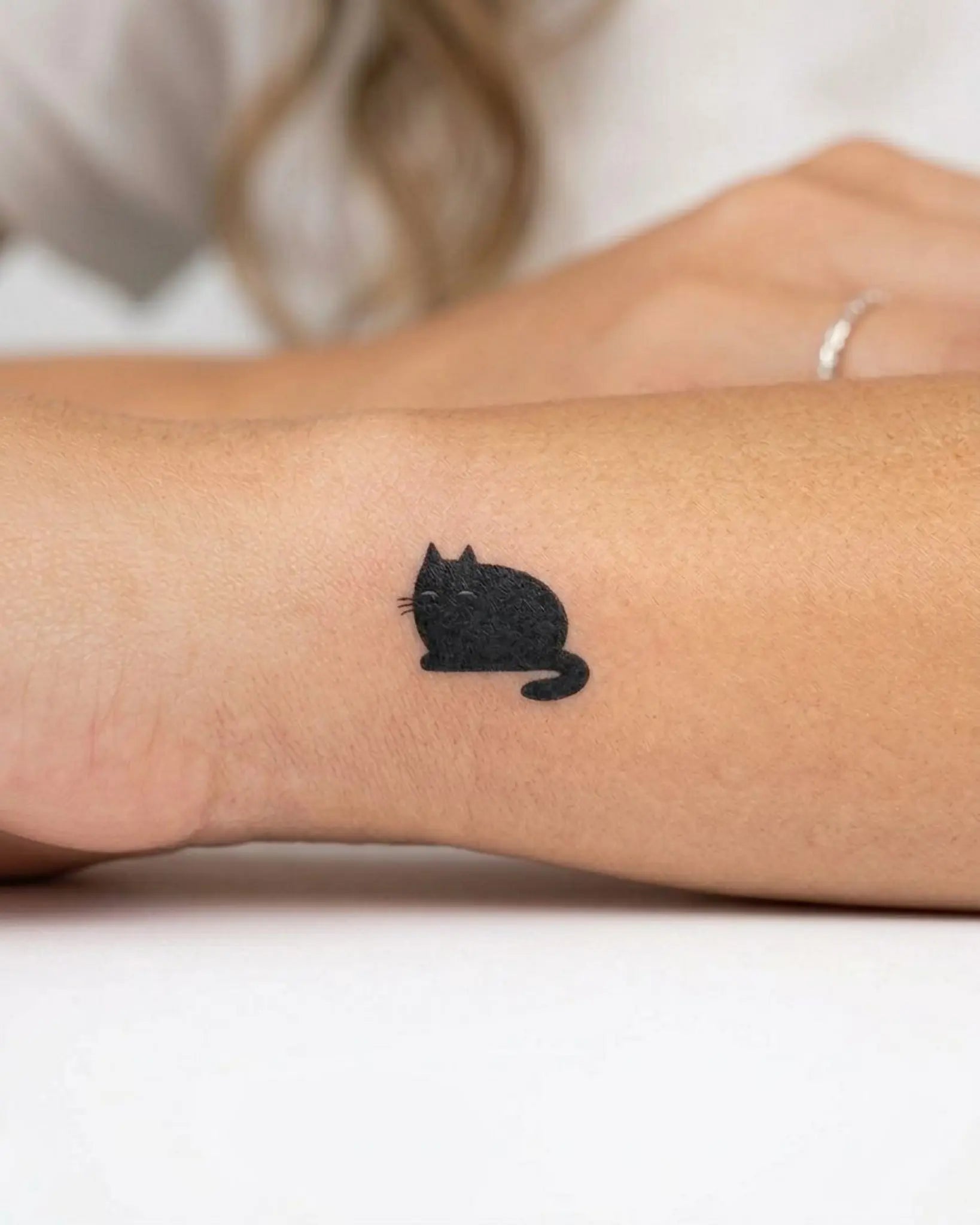 INKY Plush Cat semi-permanent tattoo applied on a woman – 0.5 x 0.5 in (1x1 cm) design, realistic ink look, lasts 10 days