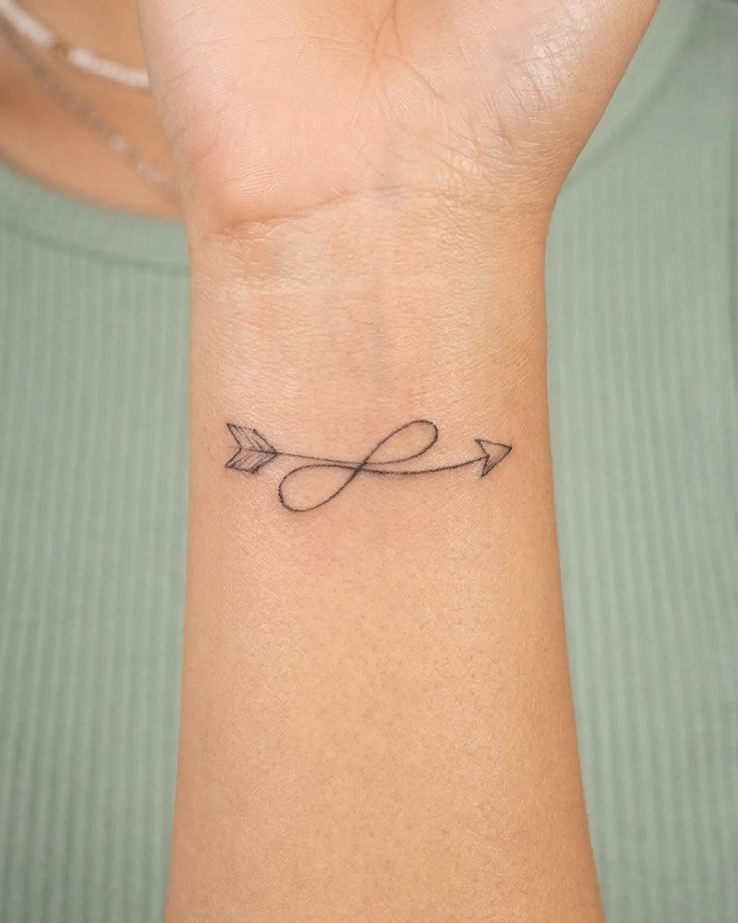 INKY Loop Arrow semi-permanent tattoo applied on a woman – 2 x 2 in (4x4 cm) design, realistic ink look, lasts 10 days