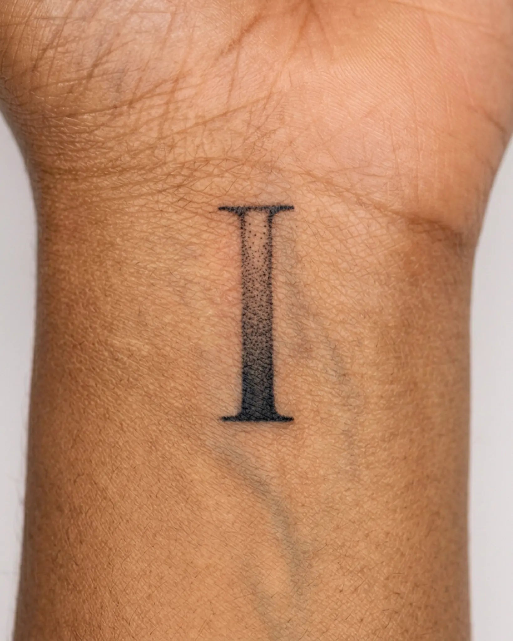 INKY Initials 1 semi-permanent tattoo applied on a woman – 2 x 2 in (4x4 cm) design, realistic ink look, lasts 10 days