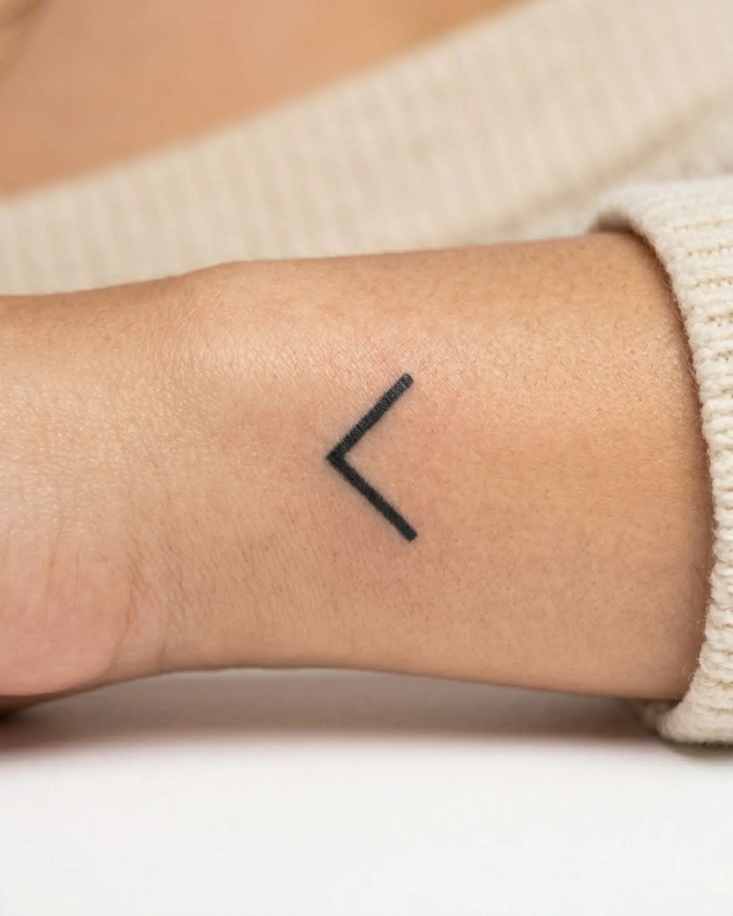 INKY Angle Left semi-permanent tattoo applied on a woman – 0.5 x 0.5 in (1x1 cm) design, realistic ink look, lasts 10 days